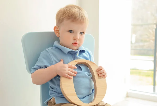 Schattige kleine jongen met letter O zitten op stoel thuis — Stockfoto