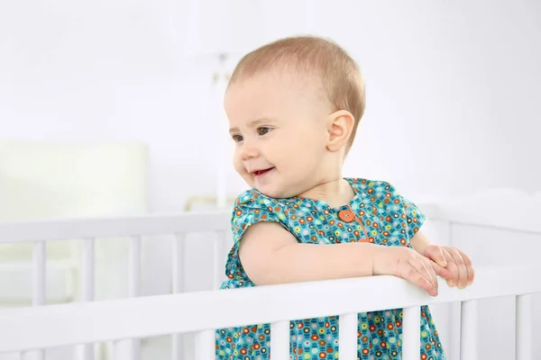 Cute little girl standing in crib at home — Stock Photo, Image