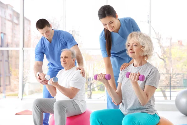 Fysiotherapeuten die werken met oudere patiënten in moderne kliniek — Stockfoto