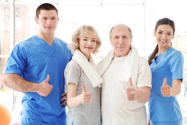 Sjukgymnaster med äldre patienter i modern klinik — Stockfoto