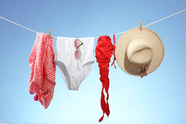 Beachwear with hat and sunglasses hanging on rope — Stock Photo, Image