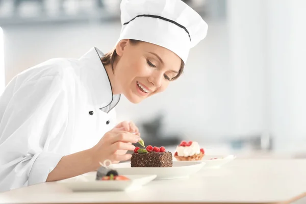 Chef femenino decorando sabrosos postres en la cocina — Foto de Stock