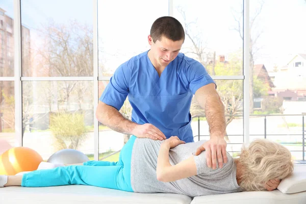 Fysiotherapeut werken met oudere patiënt in kliniek — Stockfoto