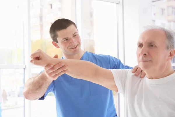 Physiotherapeut arbeitet mit älteren Patienten in Klinik — Stockfoto