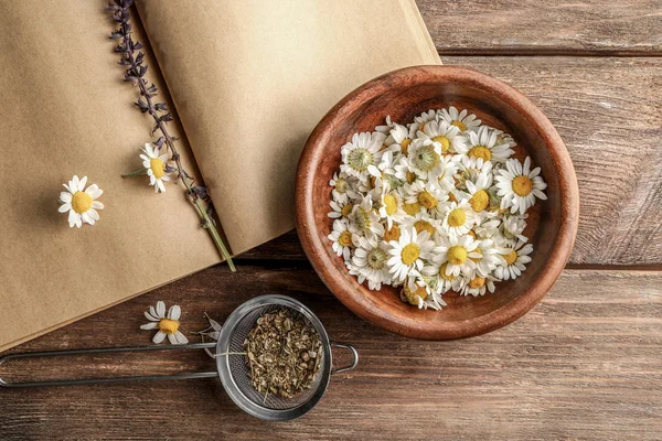 Flowers in bowl and strainer with dried chamomile — Stock Photo, Image