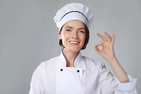 Chef feminino em fundo cinza — Fotografia de Stock