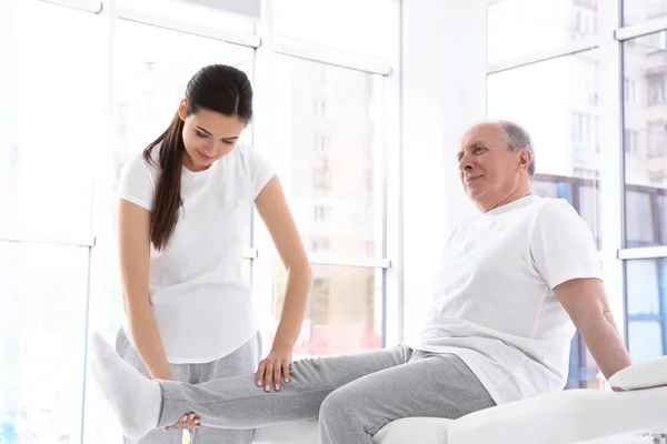 Physiotherapeut arbeitet mit älteren Patienten in Klinik — Stockfoto