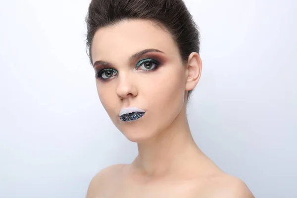 Vacker ung kvinna med kreativ makeup på ljus bakgrund — Stockfoto