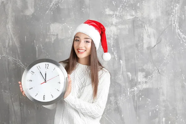 Mujer joven en Santa sombrero con reloj —  Fotos de Stock