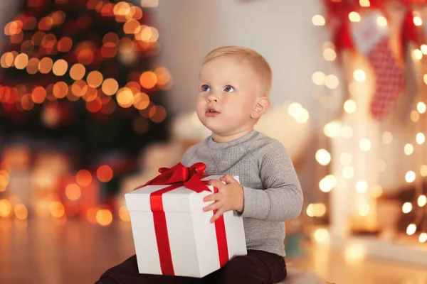 Sevimli küçük çocuk hediye kutusu için Noel odası dekore edilmiş — Stok fotoğraf