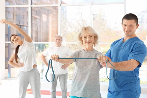 Fysiotherapeut werken met oudere patiënt in moderne kliniek — Stockfoto