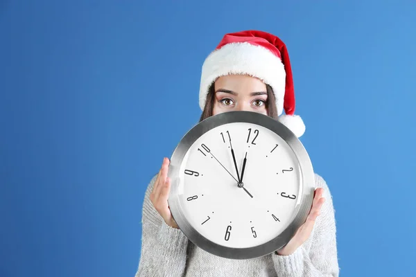 Jeune femme en chapeau de Père Noël avec horloge — Photo