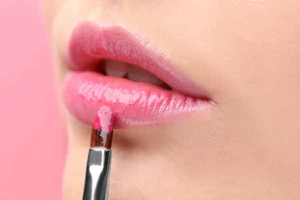 Young woman applying gloss on lips — Stock Photo, Image