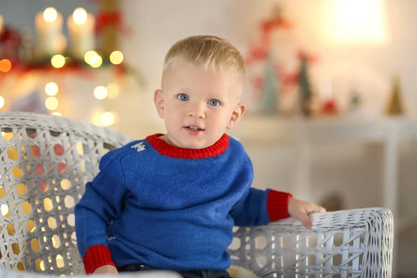 Ładny mały chłopiec siedzi w wiklinowym fotelem na niewyraźne tło — Zdjęcie stockowe