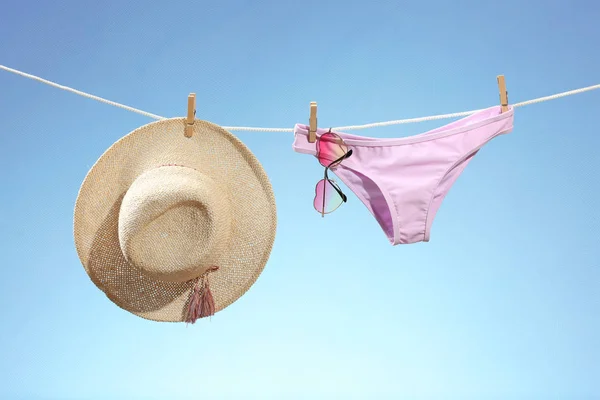 Bikini with hat and sunglasses hanging on rope — Stock Photo, Image
