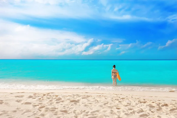 Beautiful young woman with colorful inflatable donut at sea coast — Stock Photo, Image