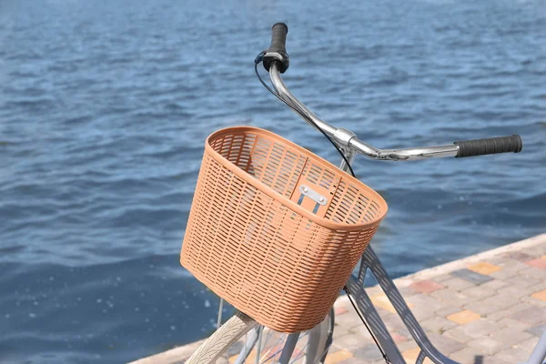 Велосипед с плетеной корзиной на набережной в солнечный день — стоковое фото