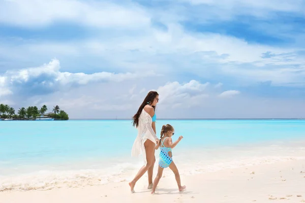 Schöne junge Frau mit Tochter am Meeresstrand — Stockfoto