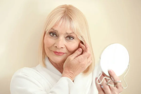 Mujer mayor aplicando crema en la cara — Foto de Stock