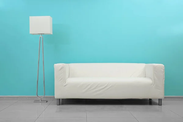 Vit soffa och golvlampa i rum nära vägg — Stockfoto