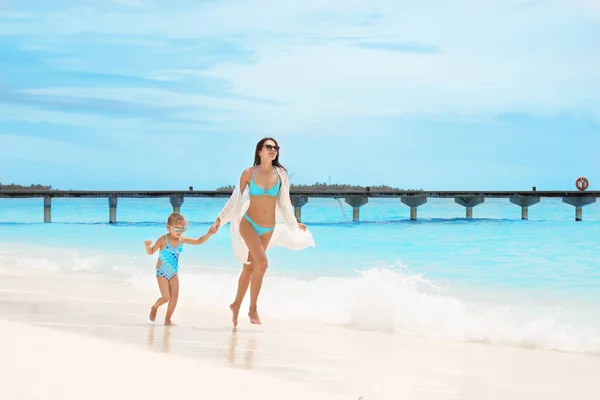 Vacker ung kvinna med dotter på strand vid havet — Stockfoto