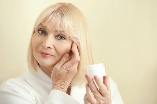 Mujer mayor aplicando crema en la cara — Foto de Stock