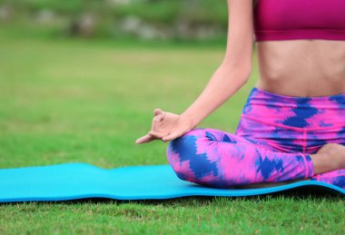 Kadın dışarıda yoga yapıyor.