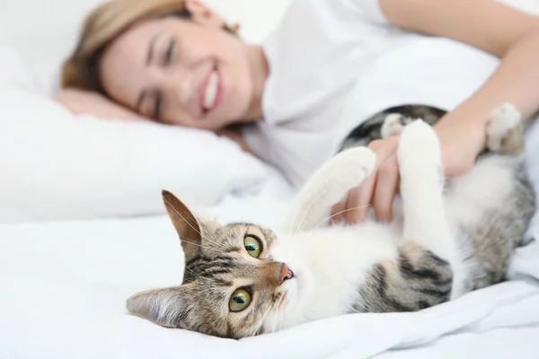 Młoda piękna kobieta z kotem, leżąc na łóżku w domu — Zdjęcie stockowe