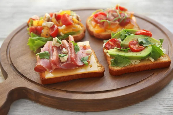 Wooden board with tasty sandwiches