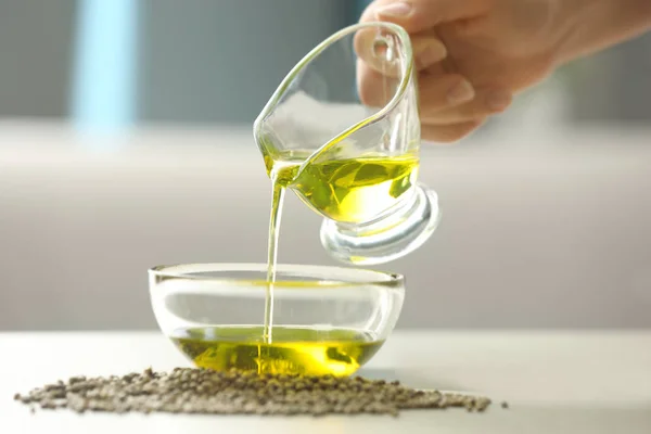 Woman pouring hemp oil in glass bowl — Stock Photo, Image