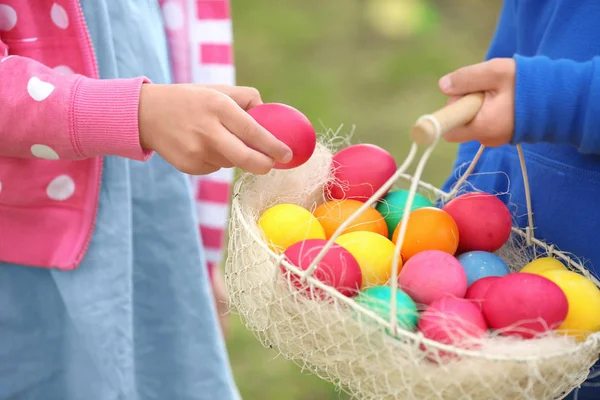 Children with basket of colorful eggs in park — Stock Photo, Image