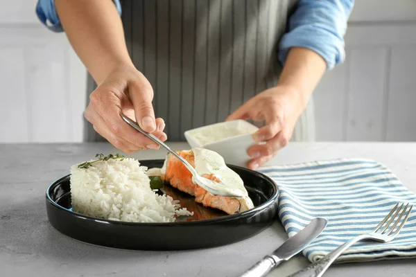 Frau gießt Lachs Sauce ein — Stockfoto