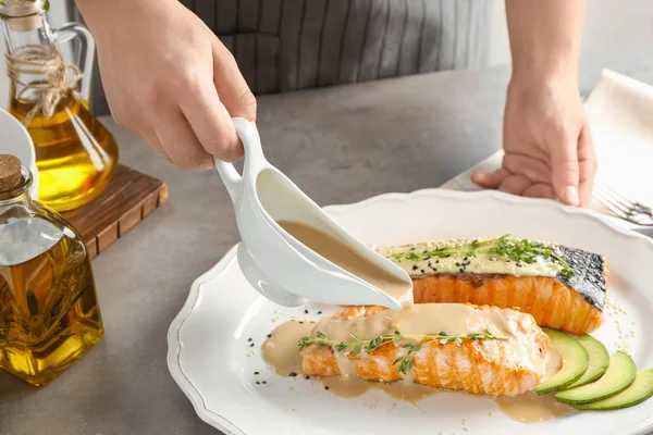 Mujer vertiendo salsa de pescado en el plato — Foto de Stock