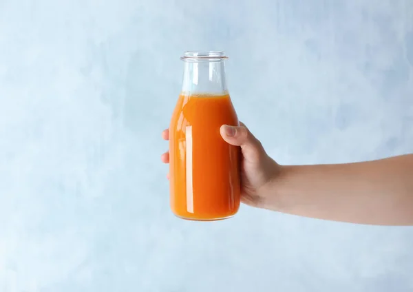 Mulher segurando garrafa de suco de cenoura — Fotografia de Stock