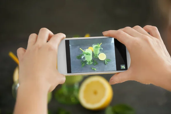 Kvinnan tar foto av smoothies med smart telefon i studio — Stockfoto
