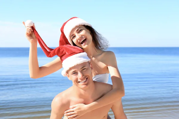 Casal em Santa chapéus na praia do mar — Fotografia de Stock