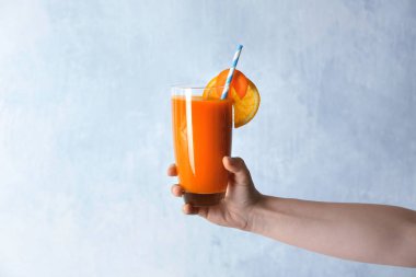 Bardak taze havuç suyu tutan kadın