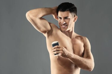 Yakışıklı delikanlı ile deodorant gri arka plan üzerinde
