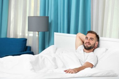 Genç adam yatağa uzanıyor. 