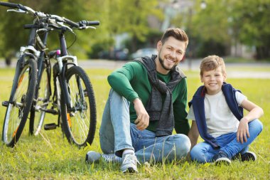 Baba ve oğul çimenlerin üzerinde oturan 