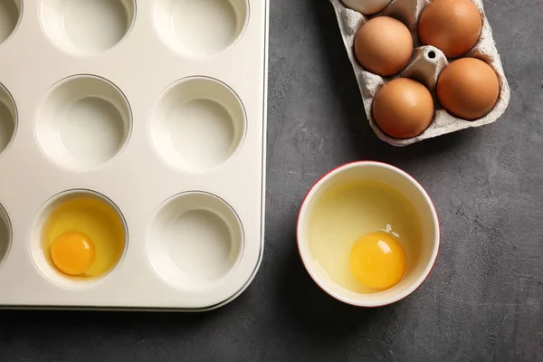 Muffin tin, skål och hållare med råa ägg — Stockfoto