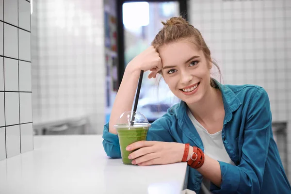 Junge Hipsterfrau trinkt Smoothie drinnen — Stockfoto