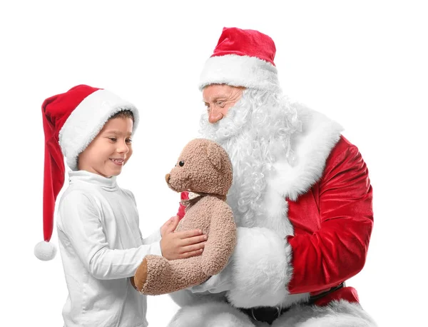 Sinterklas otentik memberikan boneka beruang kepada anak laki-laki lucu di topi Natal di latar belakang putih — Stok Foto