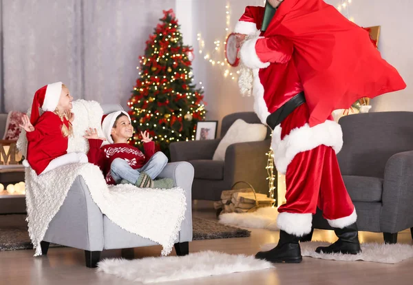 Bambini carini felici di vedere Babbo Natale con grande sacchetto regalo in camera decorato per Natale — Foto Stock