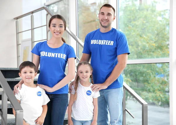 Счастливые волонтеры и дети, стоящие на лестнице в помещении — стоковое фото