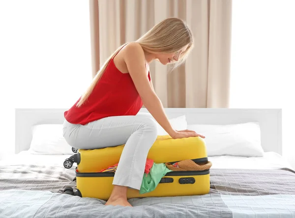 Mujer tratando de empacar su equipaje — Foto de Stock