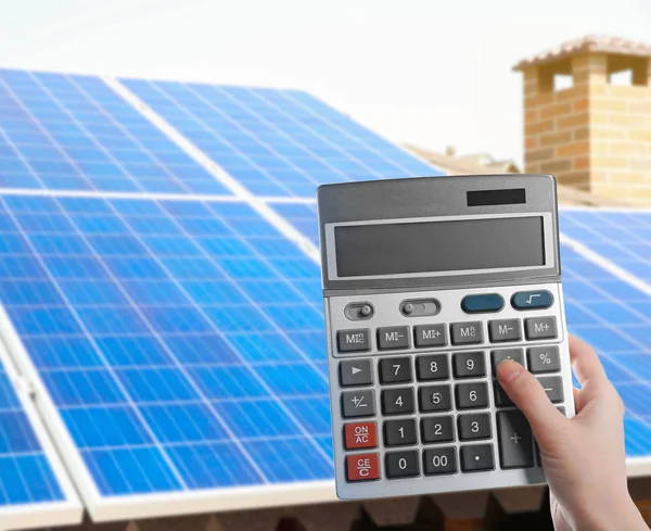 Женщина держит калькулятор и солнечные панели — стоковое фото