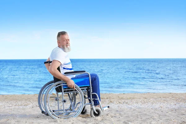 Oudere man in rolstoel aan zeekust — Stockfoto