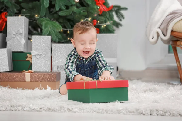 Niedliches kleines Baby mit Geschenkbox im weihnachtlich dekorierten Zimmer — Stockfoto