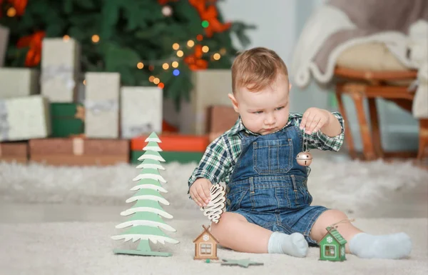 Niedliches kleines Baby mit Spielzeug im weihnachtlich dekorierten Zimmer — Stockfoto